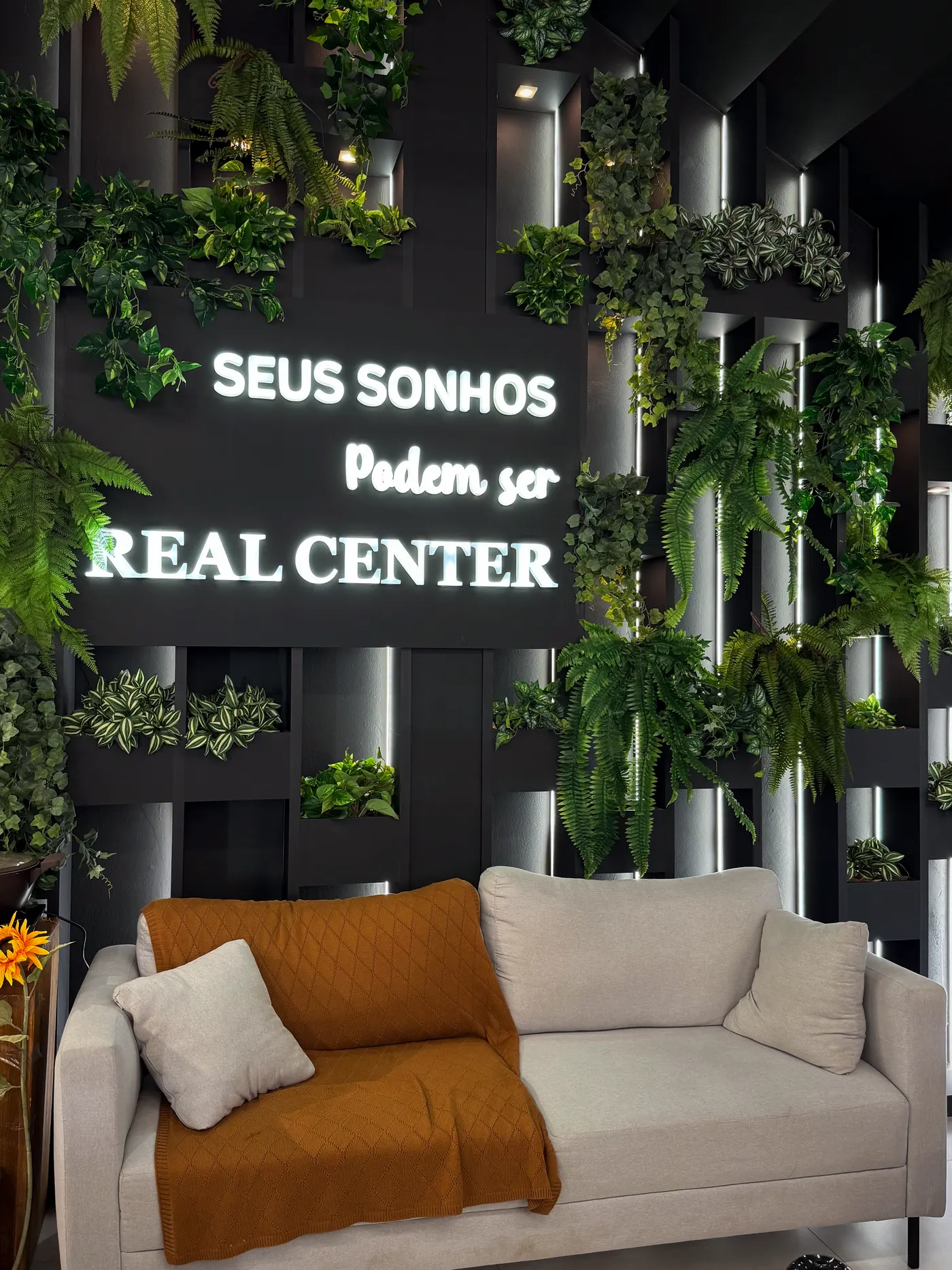 Showroom da Real Center — parede verde com o letreiro Seus sonhos podem ser Real Center
